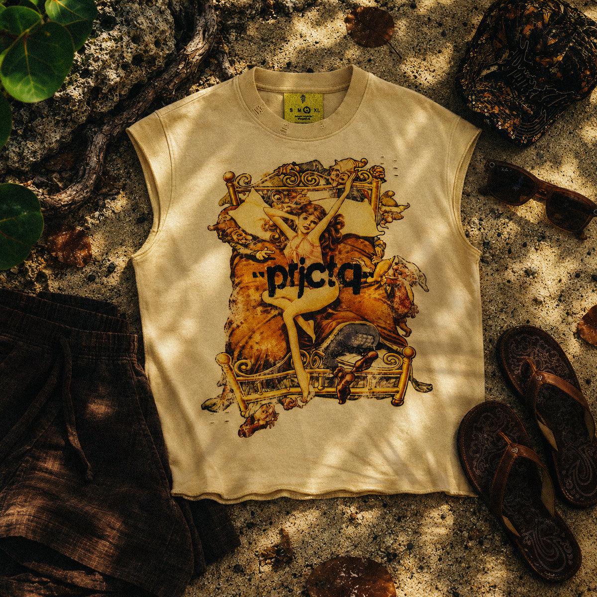 BLANCA de Project Q, camisa sin mangas crema, flat lay sobre arena con chancletas y gorra camuflaje, streetwear de Puerto Rico